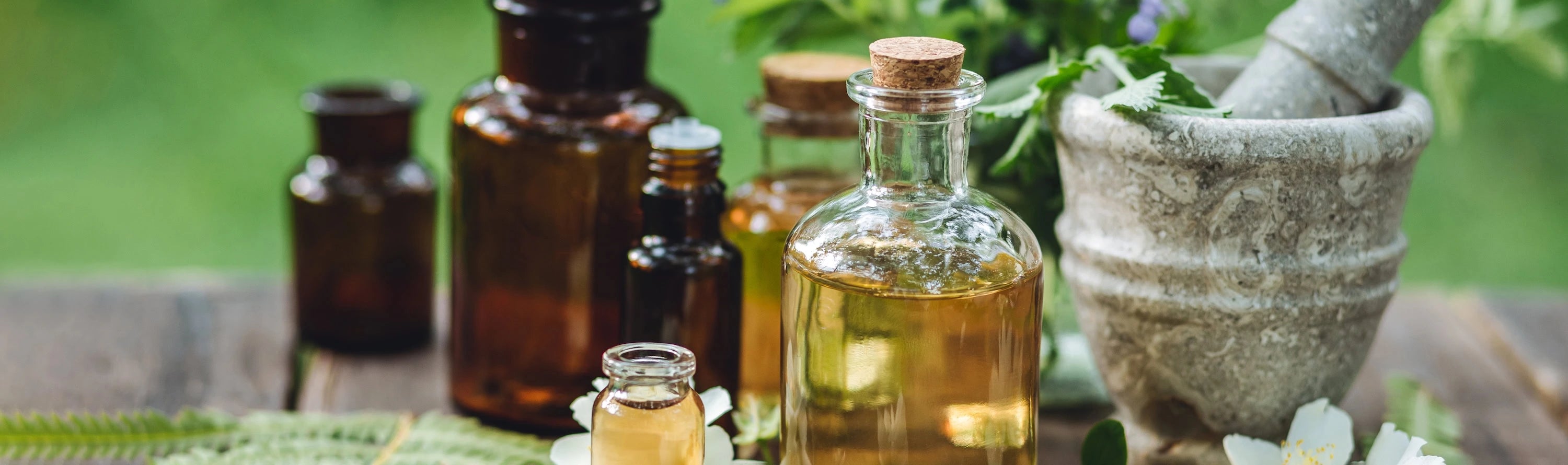 Herbal remedies with bottles, a mortar, and pestle on a wooden surface.