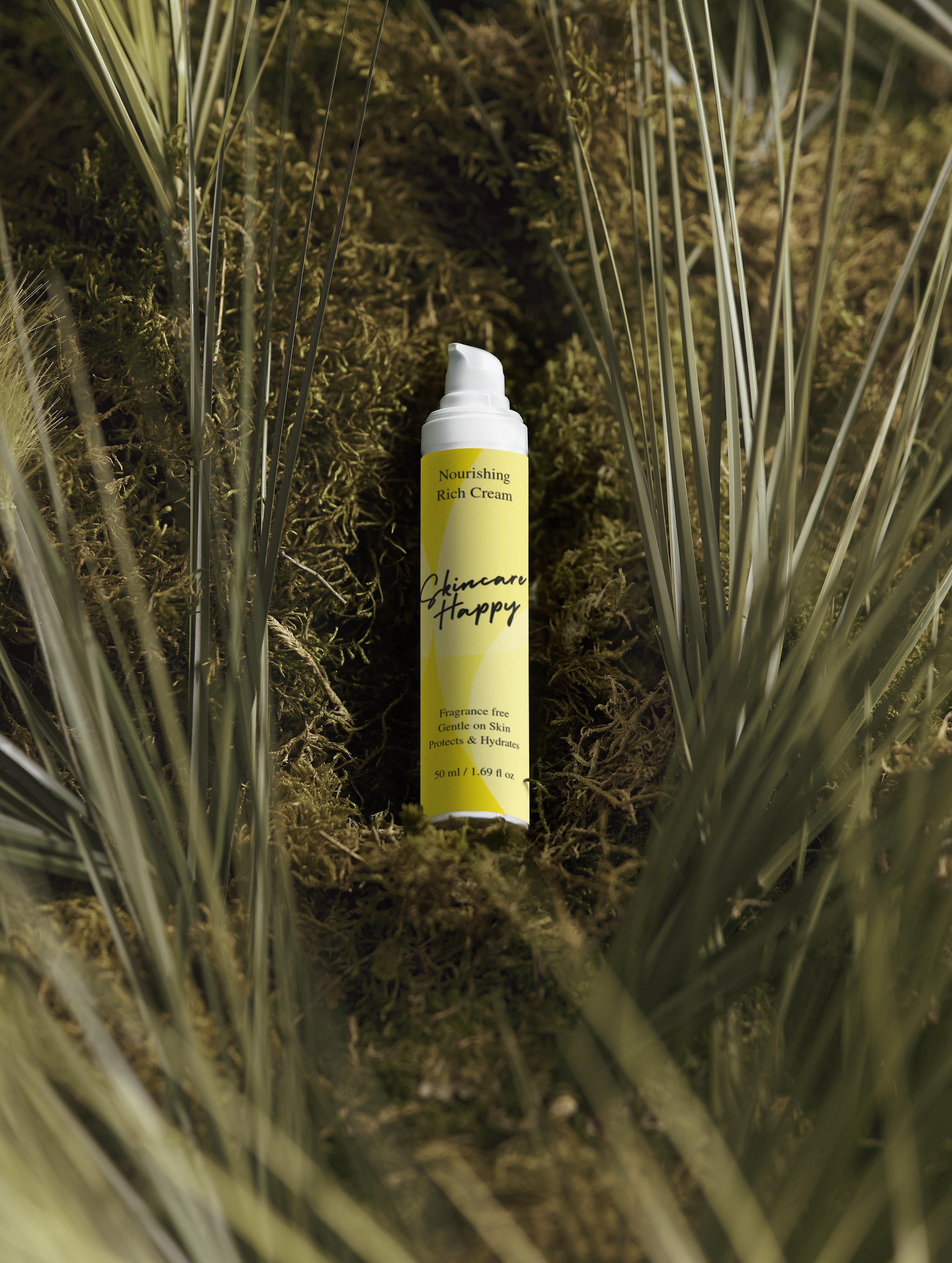 Tube of skin care product surrounded by grass and plants