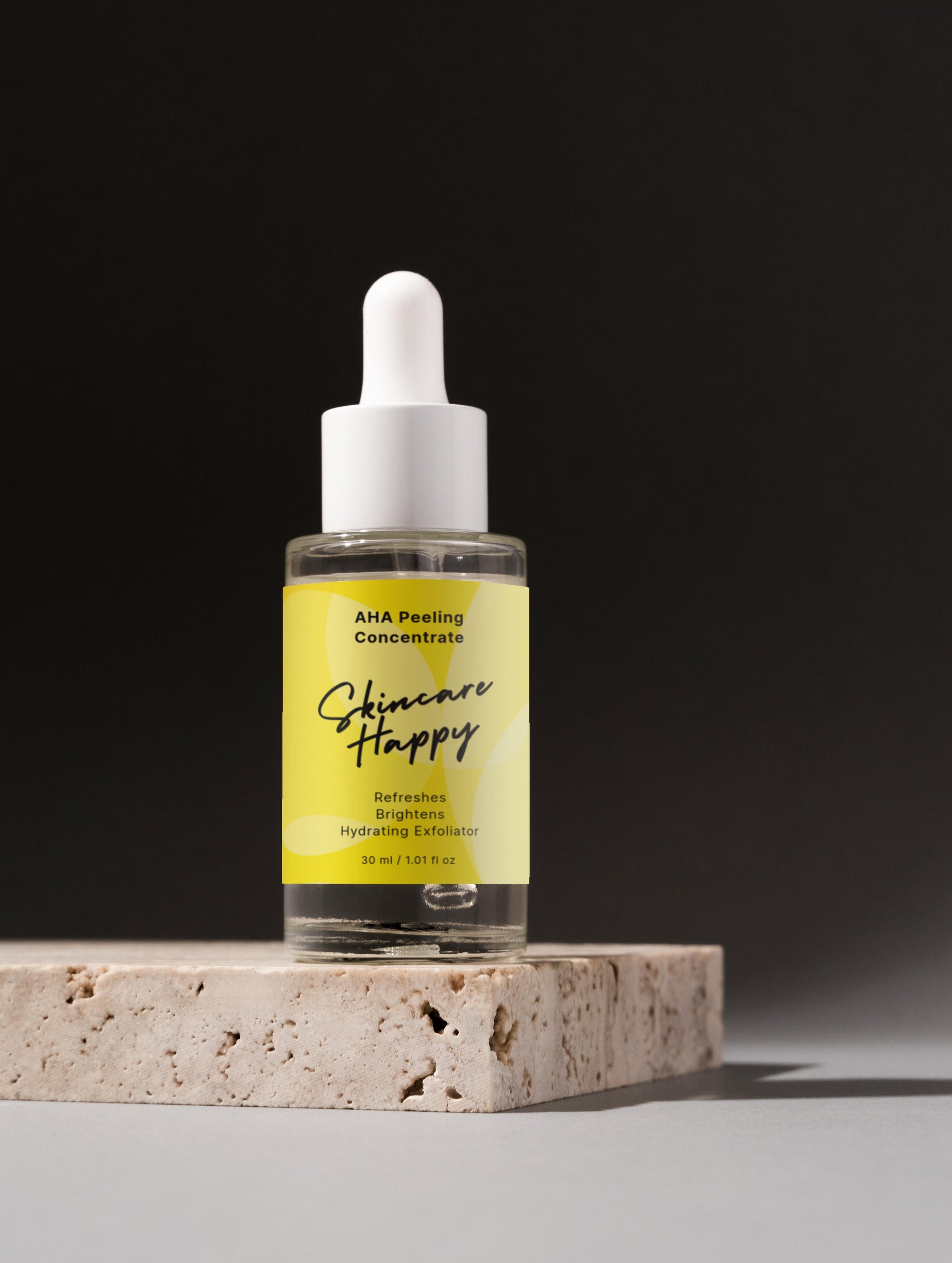 Skincare concentrate bottle with yellow label on a stone platform against a black background