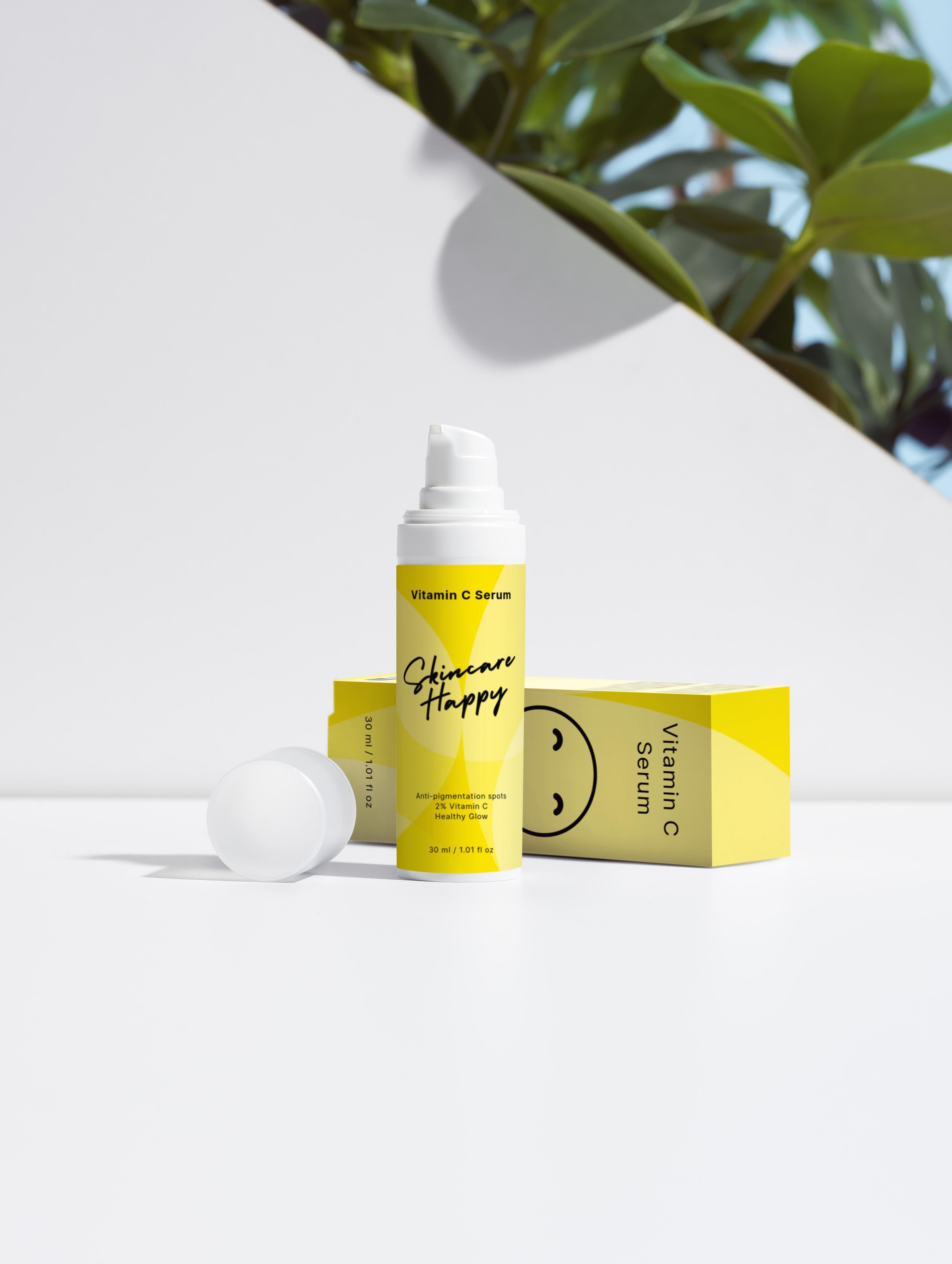 Vitamin C serum with packaging on a white surface with greenery in the background